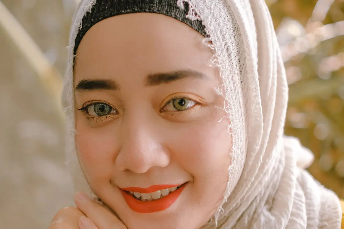 A smiling woman in a cream hijab