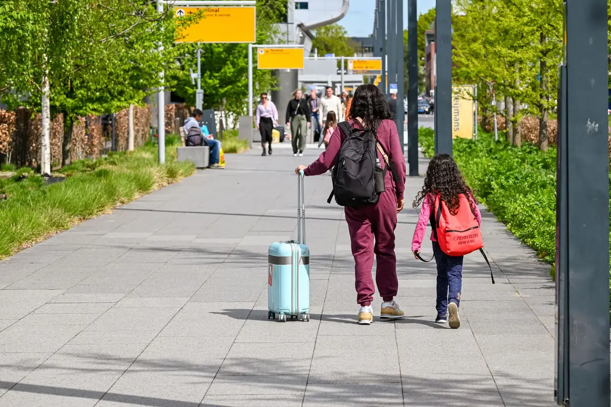 A family walking along a path with suitcases