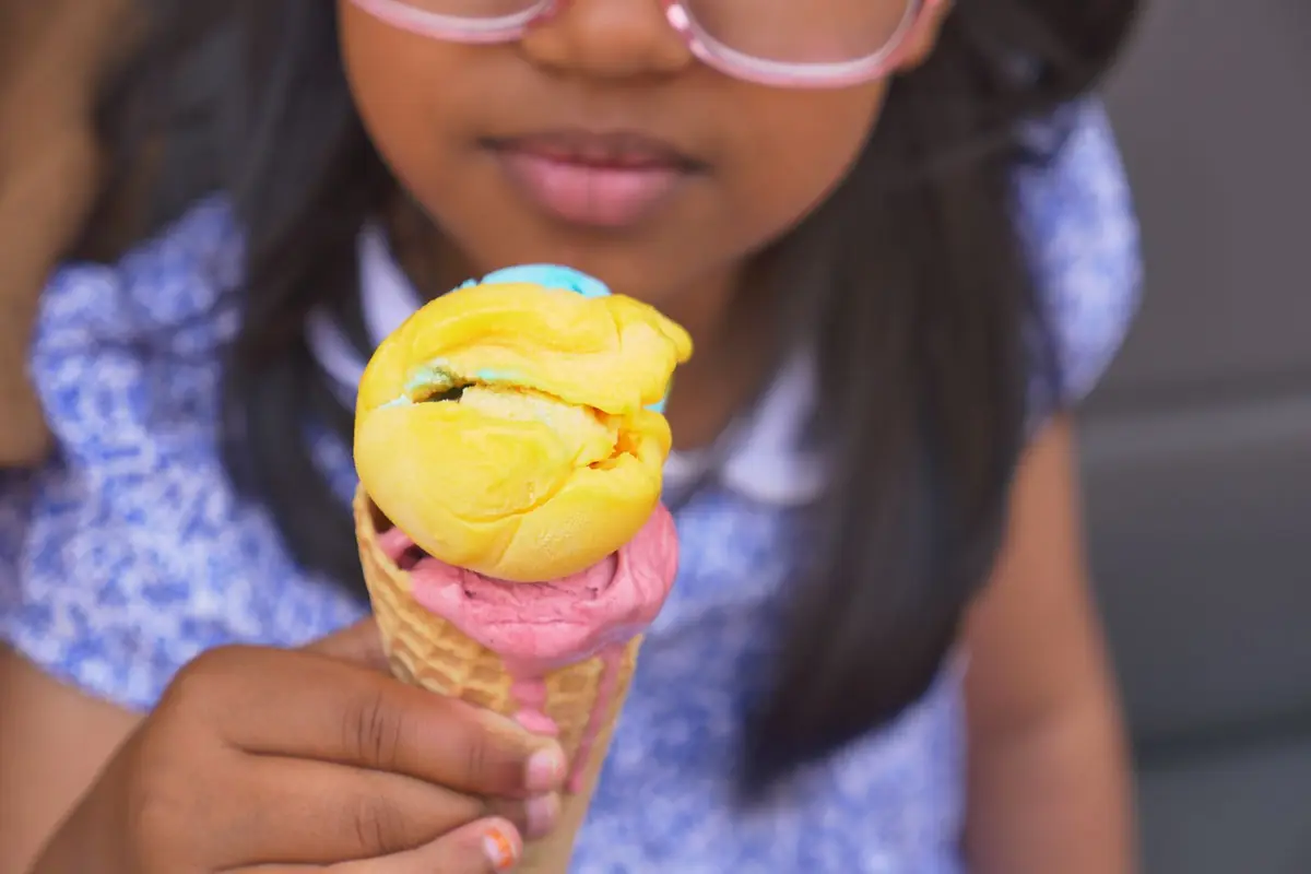 A girl holding a colourful ice cream cone