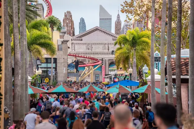 A busy theme park street with crowds heading in