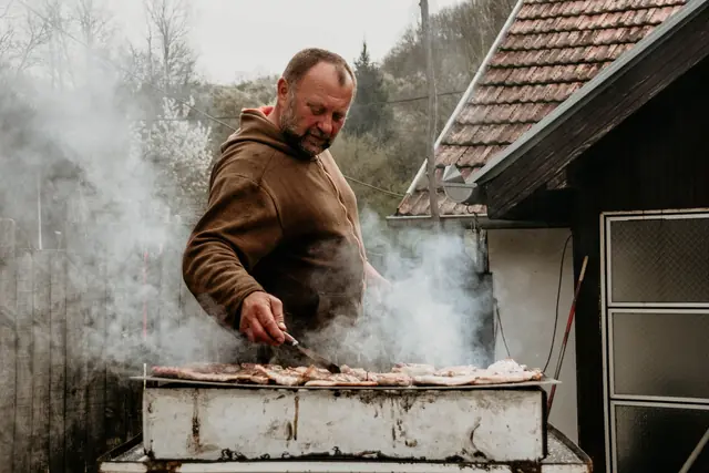 A man grilling meat over charcoal in Serbia