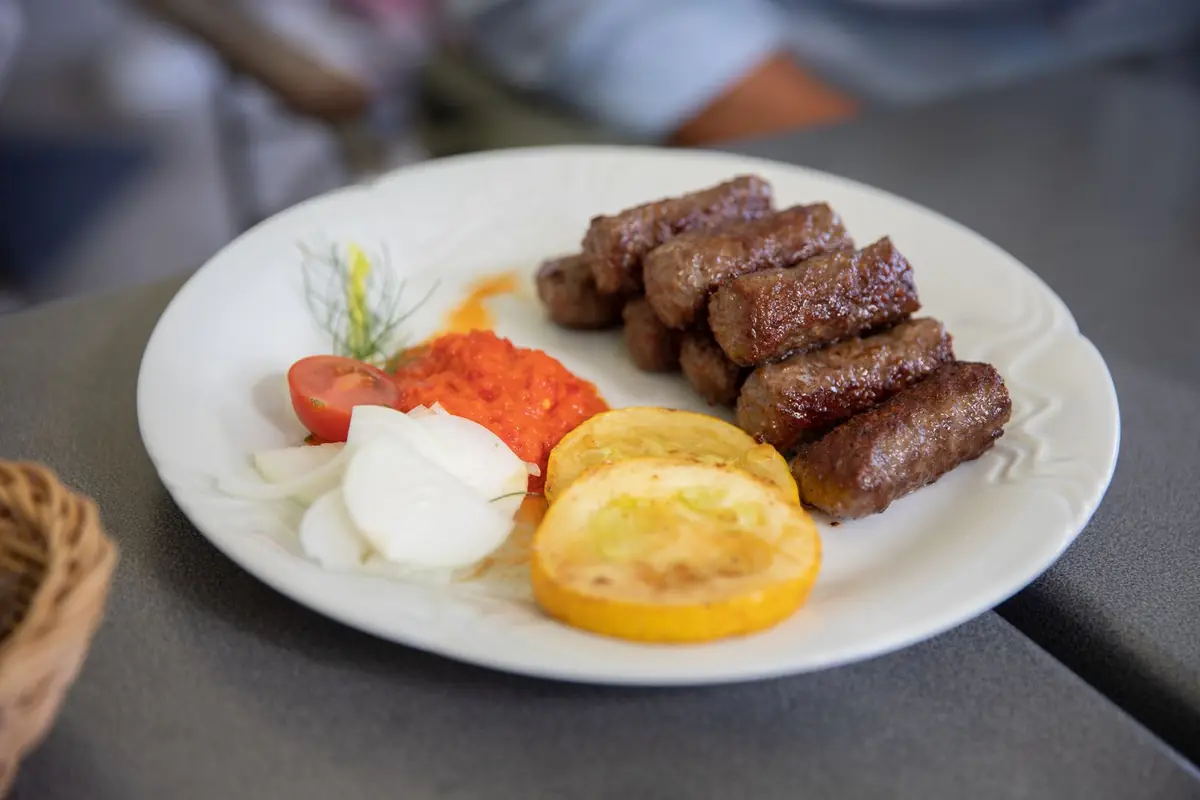 A plate of Serbian grilled meat rolls with cream and sides